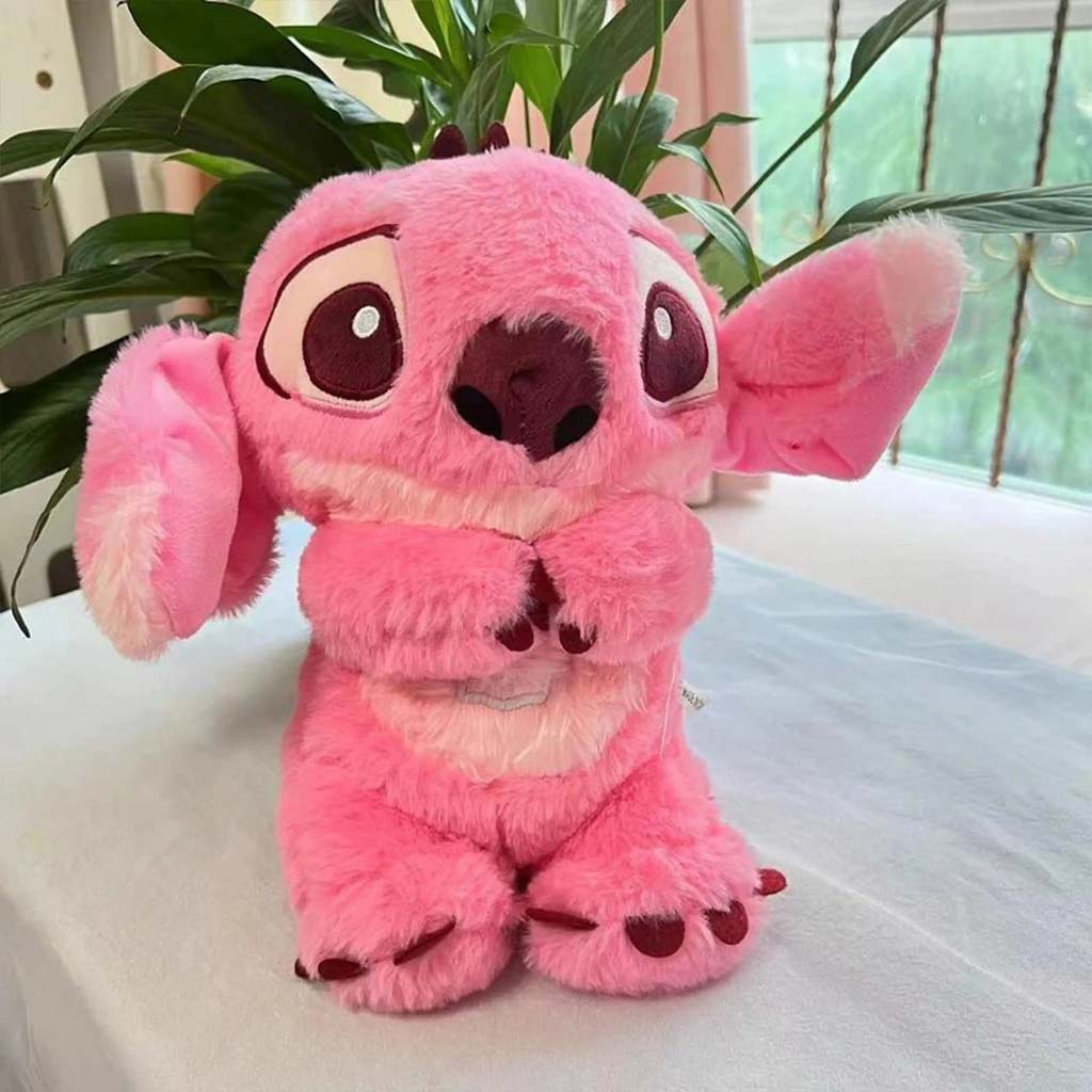 Pelúcia rosa do Stitch com expressão fofa, sentada sobre mesa branca com plantas ao fundo.