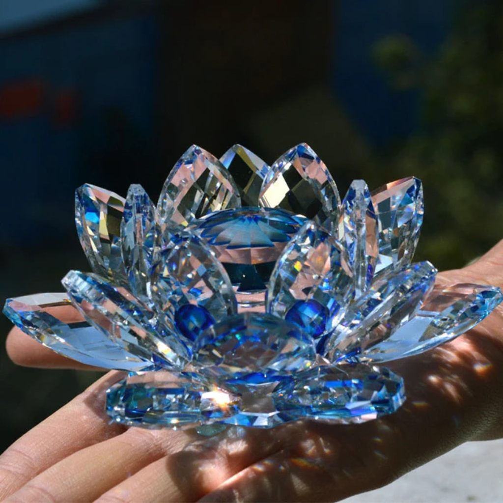 Flor de Lótus de Cristal Feng Shui com pétalas facetadas em tons de azul, refletindo a luz para simbolizar paz e serenidade espiritual. Pelicano Azul.