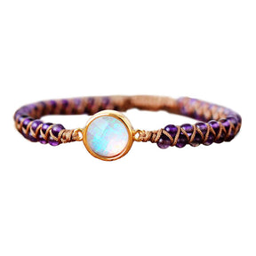 Pulseira com contas de ametista e um cristal opalescente central, entrelaçada com um cordão marrom, Pelicano Azul.