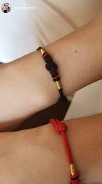 Avaliação de cliente mostrando duas pulseiras de nó tibetanas, uma em cordão preto e outra em vermelho, com detalhes dourados