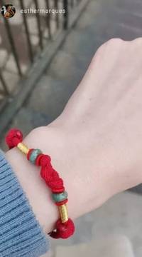 Avaliação de cliente mostrando pulseira de nó tibetana em cordão vermelho com detalhes dourados e verdes, simbolizando proteção