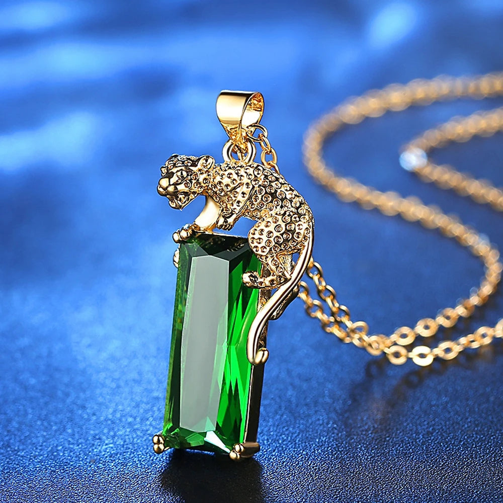  Colar com pingente de leopardo dourado sobre cristal verde retangular e corrente delicada com acabamento brilhante.