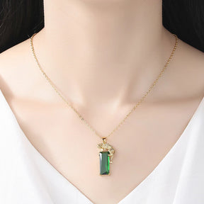 Colar de pingente leopardo dourado com cristal verde retangular, usado no pescoço com corrente delicada.