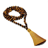 Japamala Olho de Tigre com contas de pedras naturais em tons dourados e marrons, finalizado com um tassel dourado. Utilizado para meditação e equilíbrio espiritual, o Japamala é ideal para a prática de mantras e promove serenidade e foco. Pelicano Azul.