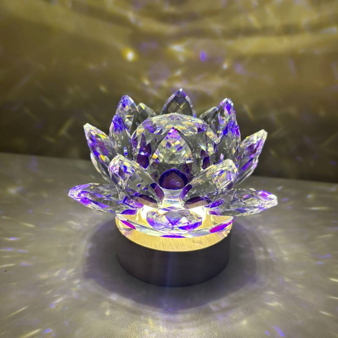 Luminária Flor de Lótus Cristal com reflexos roxos e dourados, criando um efeito de luz calmante e harmonioso no ambiente. Pelicano Azul.