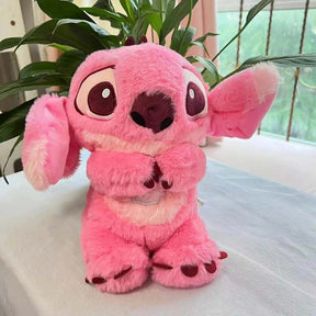 Pelúcia rosa do Stitch com expressão fofa, sentada sobre mesa branca com plantas ao fundo.