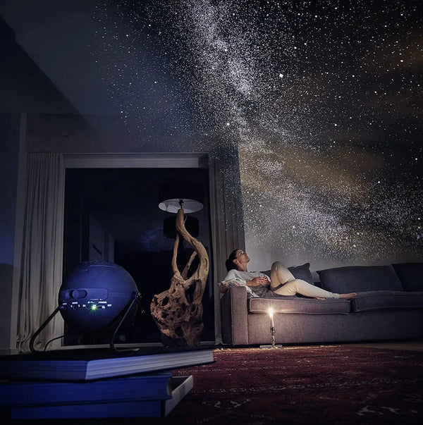 Sala com projeção de céu estrelado no teto e parede, criando uma atmosfera relaxante com o Projetor de Galáxia Pelicano Azul.