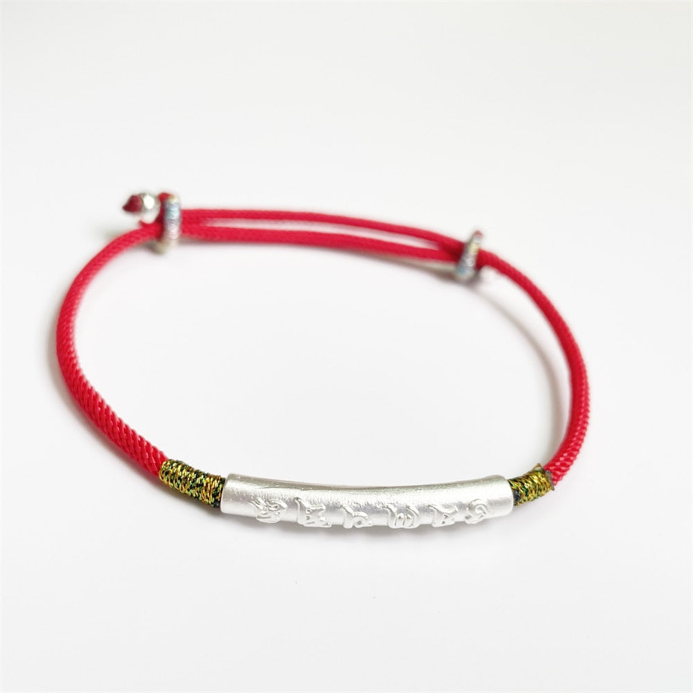 Pulseira Vermelha Tibetana Protetora com detalhe em prata e cordão ajustável. Possui inscrições tibetanas gravadas, ideal para proteção espiritual e harmonia. Pelicano Azul.