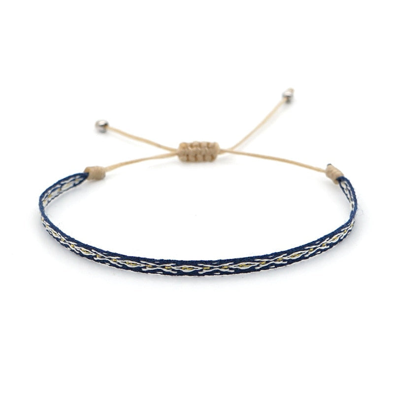 Pulseira Budista fina, trançada em azul escuro e branco, parte do conjunto com bracelete em Prata Tibetana. Pelicano Azul.