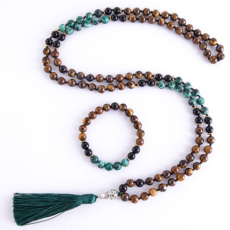 Japamala com 108 contas em Ônix Negro, Olho de Tigre e Turquesa Africana, com um elegante tassel verde. Acompanha pulseira combinando Pelicano Azul