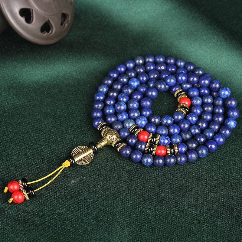 Japamala Tibetano com 108 contas de Lápis Lazúli, ornamentos dourados e vermelhos, ideal para práticas de elevação espiritual e meditação profunda Pelicano Azul.