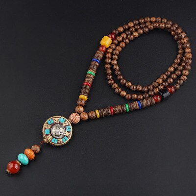 Japamala Vintage em madeira envelhecida do Nepal com 108 contas, mostrando detalhes coloridos e um pendente ornamental em dourado - Pelicano Azul.