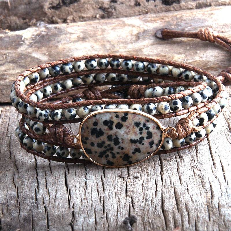 Pulseira Fashion com pedra central de dalmatian jasper, decorada com contas de pedras naturais em tons neutros e acabamento em couro trançado - Pelicano Azul.