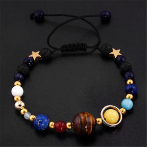 Pulseira planetária ajustável com esferas representando planetas e detalhes dourados, incluindo estrelas e um sistema solar, Pelicano Azul.