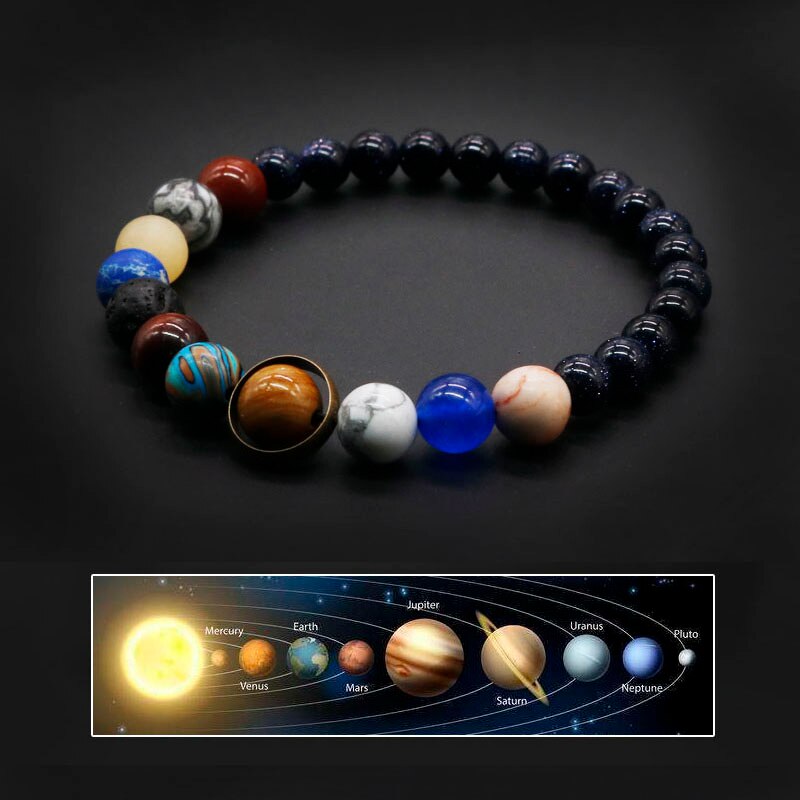 Pulseira com esferas que representam os planetas do sistema solar em cores vibrantes sobre um fundo preto, Pelicano Azul.