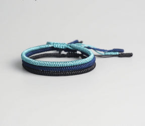 Conjunto de três pulseiras Budistas em tons de azul e preto, simbolizando prosperidade e equilíbrio. Pelicano Azul.